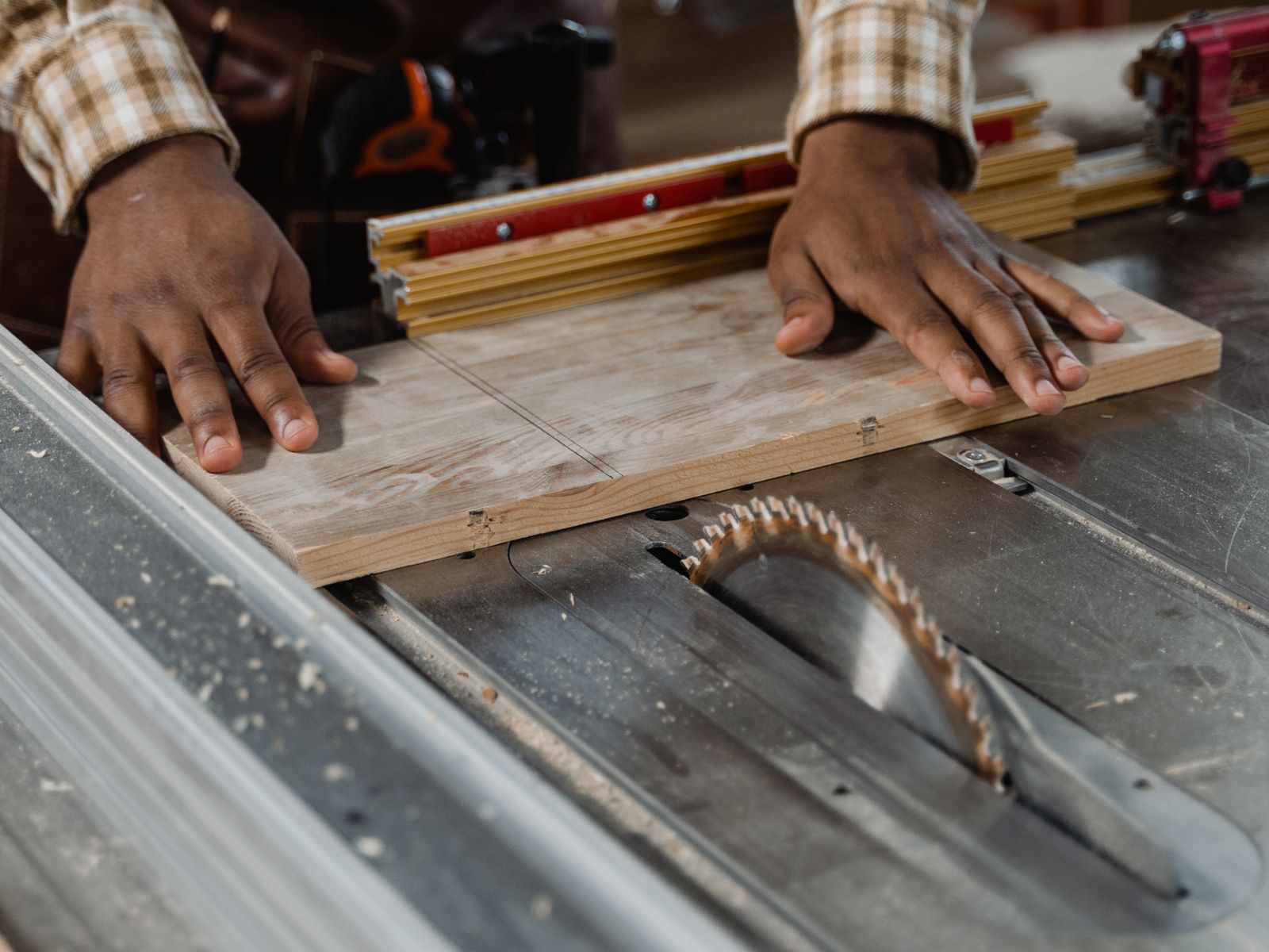 A tradesperson's hands guiding a board through a saw — hands-on local work.